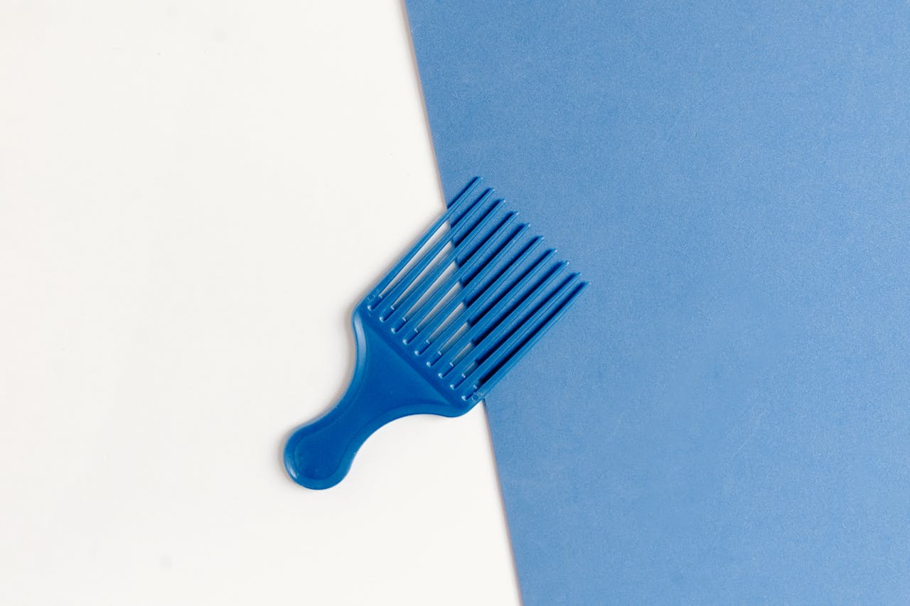 Stylish blue plastic comb on a dual-tone white and blue background.