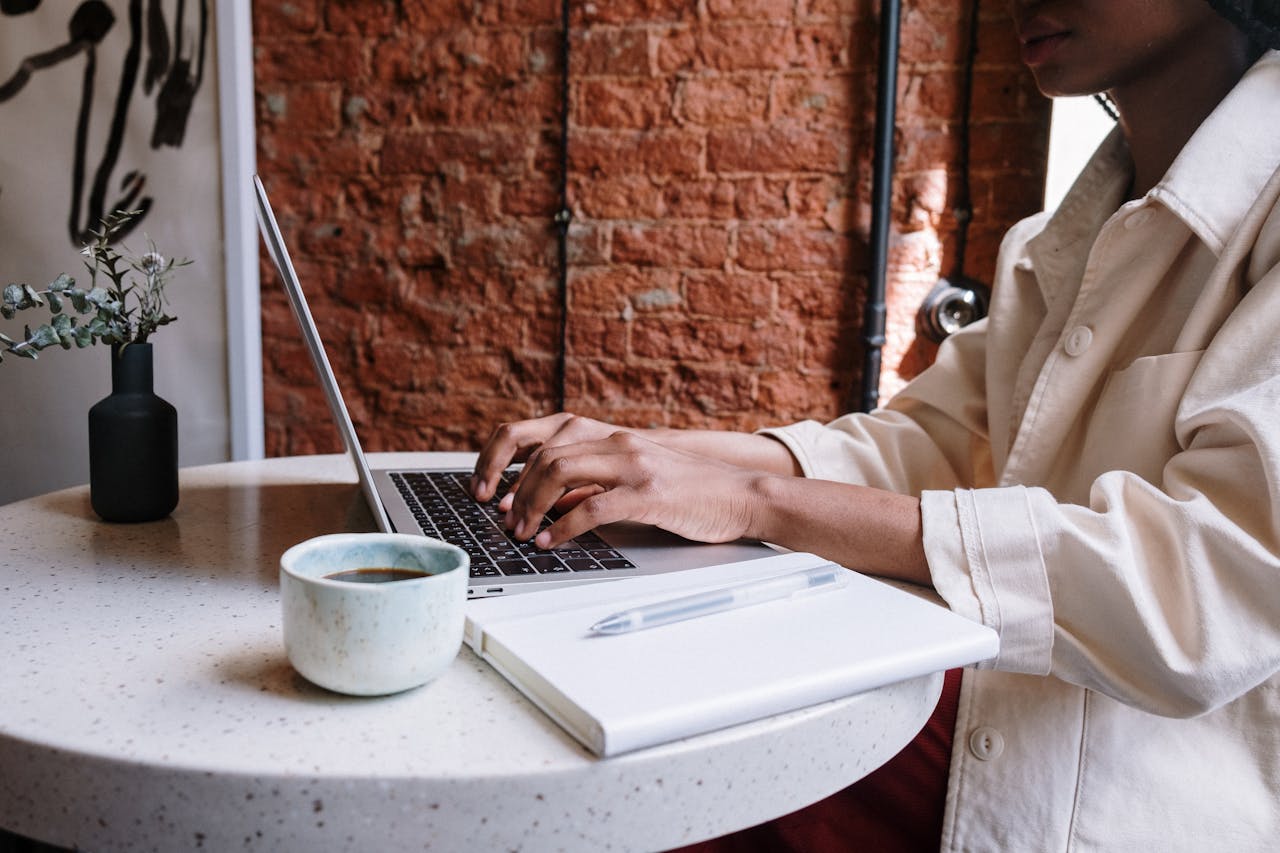 services-02 Woman working on a laptop with coffee in a cozy café, highlighting a productive and modern vibe.